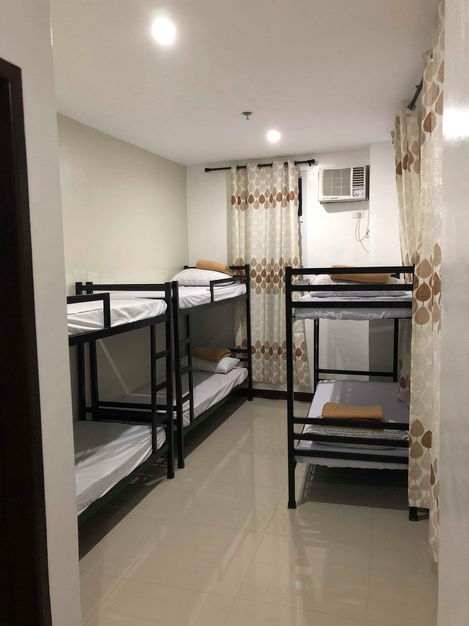 A dormitory room with bunk beds, a ceiling fan, and an air conditioning unit.