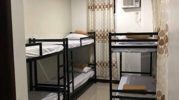 A dormitory room with bunk beds, a ceiling fan, and an air conditioning unit.