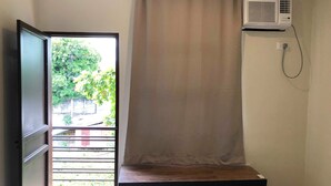 A room with a window, an air conditioner, and a wooden bench. - Golite Hostel (Legazpi)
