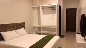 A neatly arranged bedroom with a bed, a wardrobe, and a TV. - Golite Hostel (Legazpi)