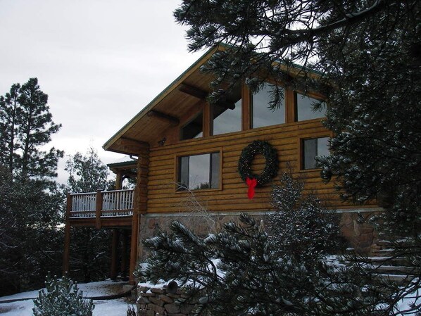 A wooden cabin with a balcony, surrounded by snow-covered trees. - Spa style log cabin retreat on Sandia Mountain (Cedar Crest)