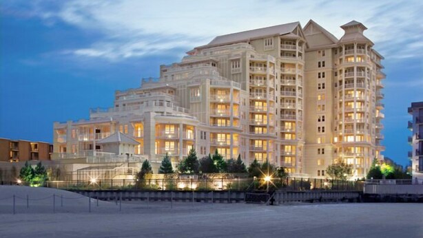 Un hôtel à plusieurs étages au design moderne, doté de balcons et de grandes fenêtres.