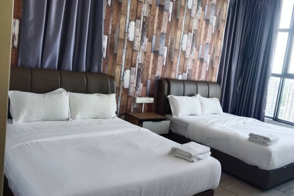 Habitación de hotel con dos camas, un panel de pared de madera, una mesita de noche y un ventanal con vistas a la ciudad.