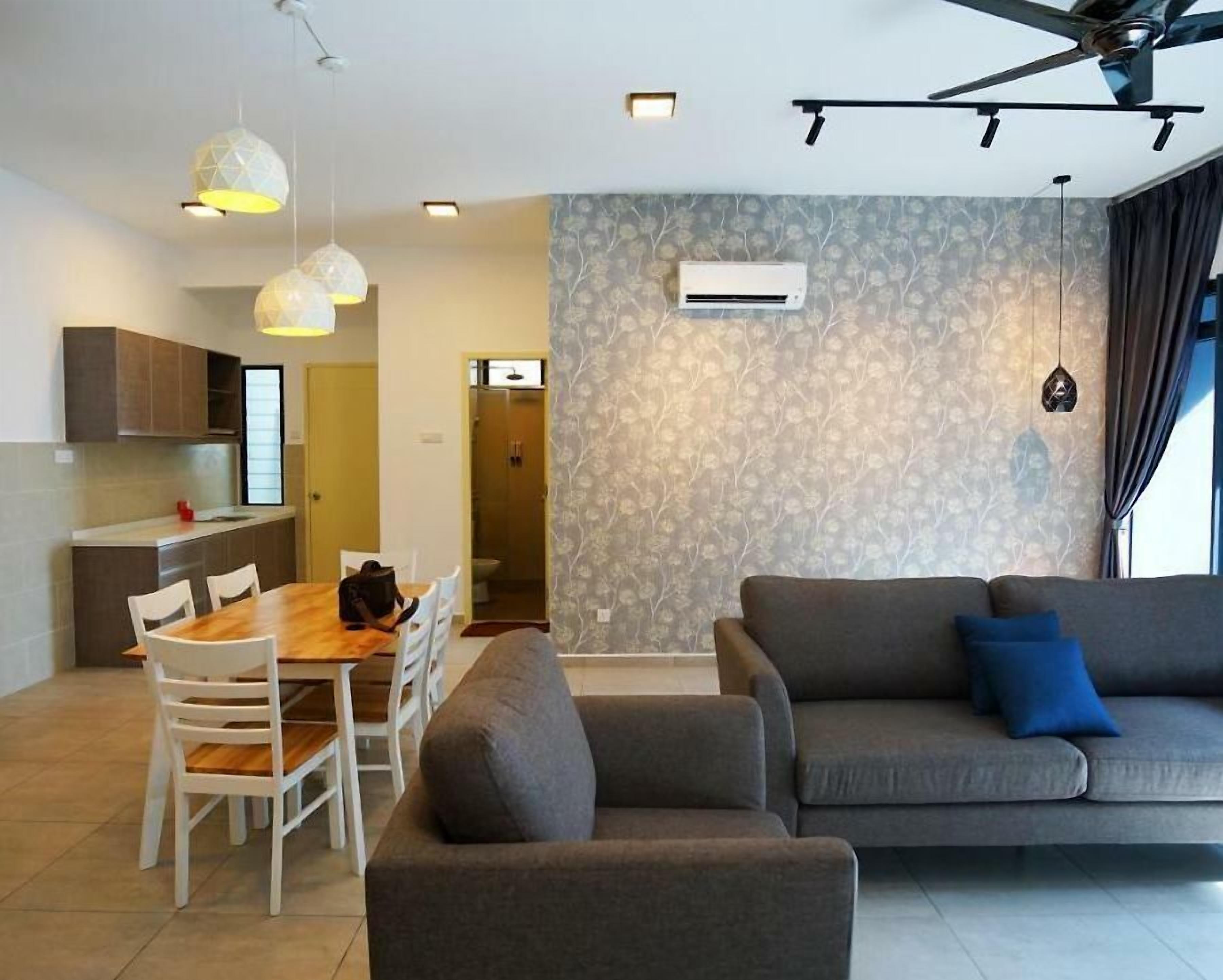 A modern living room with a grey sofa, a dining table with chairs, and pendant lighting.