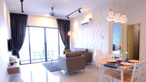 A modern living room with a sofa, dining table, and chairs. - Atlantis Residence Iconstay Design Apartment by Iconstay Melaka (Malacca City)