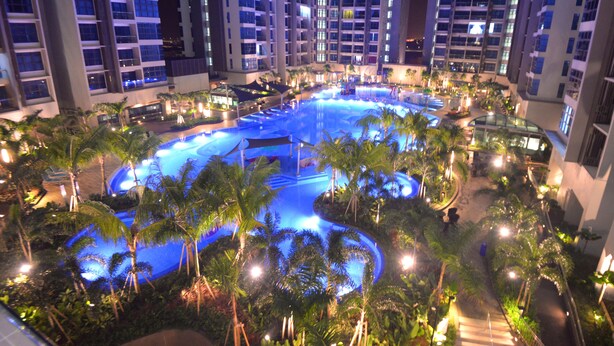 A large indoor swimming pool surrounded by palm trees and modern buildings. - Atlantis Residence Iconstay Design Apartment by Iconstay Melaka (Malacca City)