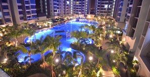 A large indoor swimming pool surrounded by palm trees and modern buildings. - Atlantis Residence Iconstay Design Apartment by Iconstay Melaka (Malacca City)