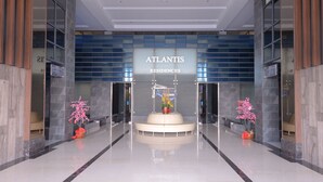 A modern lobby with a central seating area, a sign reading "Atlantis Residences," and two potted plants. - Atlantis Residence Iconstay Design Apartment by Iconstay Melaka (Malacca City)
