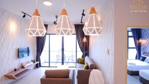 A modern hotel room with a sofa, a TV, and pendant lights. - Atlantis Residence Iconstay Design Apartment by Iconstay Melaka (Malacca City)
