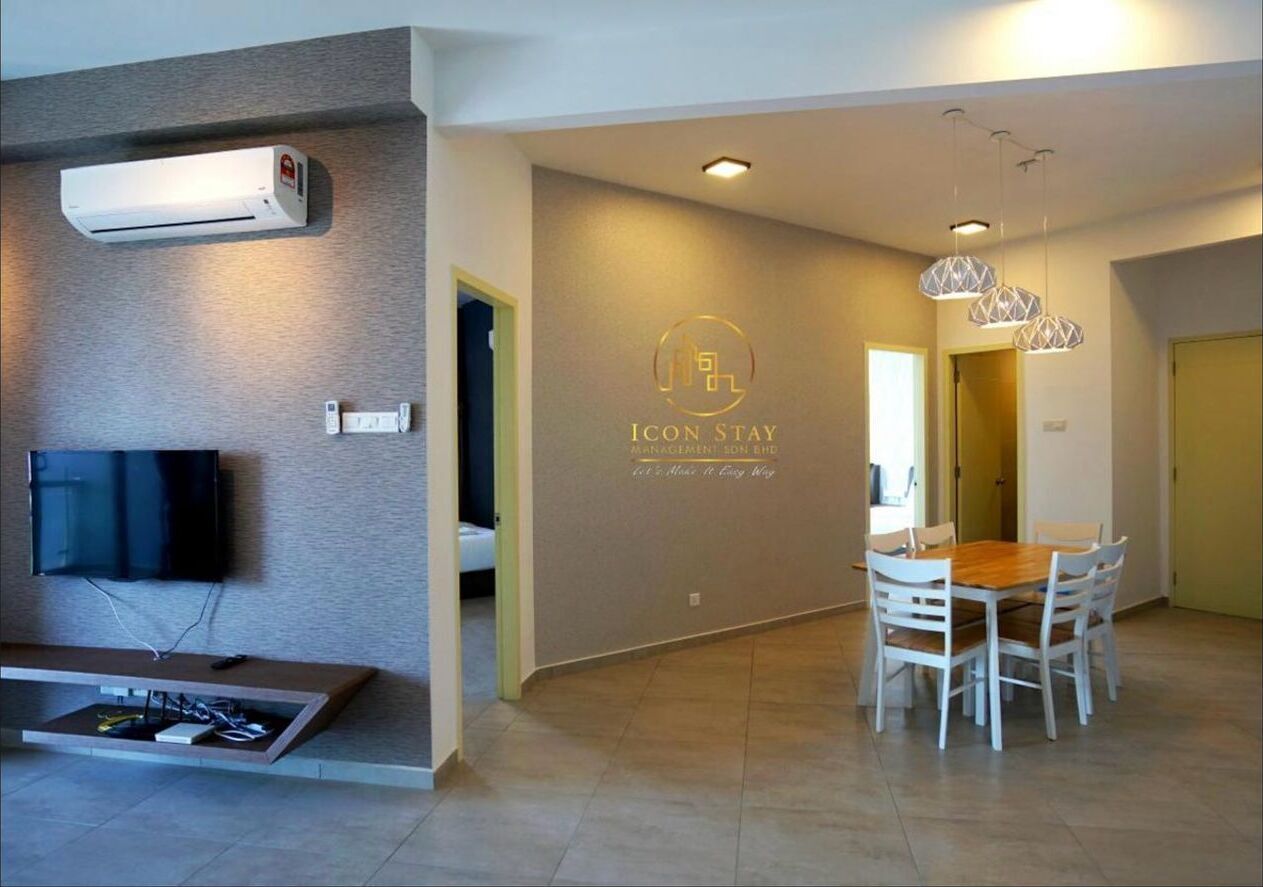 A modern hotel room with a flat-screen TV, air conditioning unit, and a dining area with a wooden table and chairs.