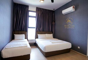 Ein Hotelzimmer mit zwei Betten, einem Fenster mit Vorhängen, einer Klimaanlage und einem Logo an der Wand.