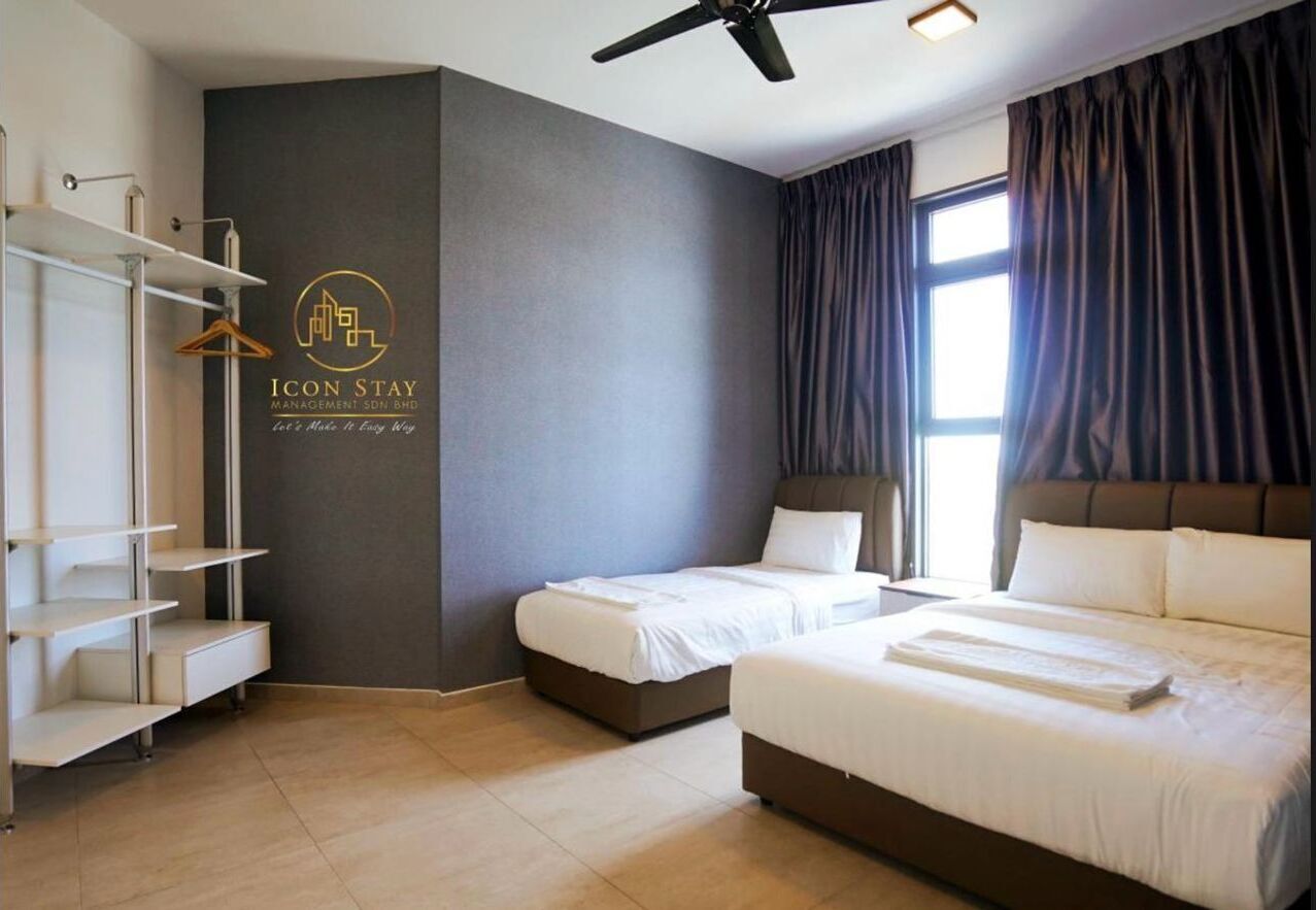 A hotel room with two beds, a wardrobe, a ceiling fan, and a large window with curtains.