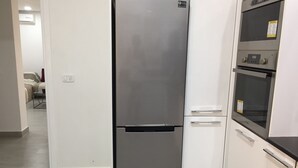 A modern kitchen with a stainless steel refrigerator, a built-in oven, and white cabinetry.