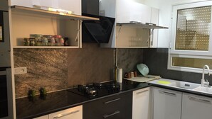 A modern kitchen with a black countertop, white cabinets, a gas stove, and a window with blinds.