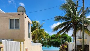 Un bâtiment situé sur la côte, doté d’une antenne parabolique, d’une clôture blanche et offrant une vue sur l’océan.
