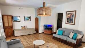Un salon avec un canapé, une petite table, un téléviseur et un fauteuil en osier.