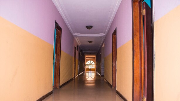 A hallway with a tiled floor and doors on both sides. - Jolac Hotel And Suites (Lagos)