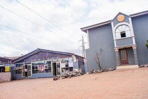 A building with a large glass entrance, a clock above the door, and a stone wall in front. - Jolac Hotel And Suites (Lagos)