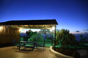 Eine Terrasse im Freien mit Tisch und Stühlen, einer Reetdachkonstruktion und Blick auf das Meer.