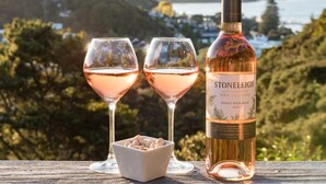 A bottle of Stonleigh Pinot Noir Rose 2019 on a wooden surface with two glasses of wine and a bowl of nuts. - Allure Lodge cabin (Paihia)