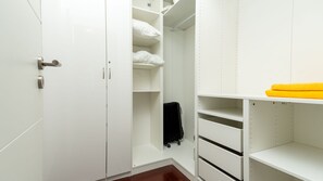A white closet with shelves and drawers, a radiator, and a yellow towel. - Casa Eleanor by LovelyStay (Estreito da Calheta)