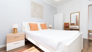 A bedroom with a bed, nightstands, a dresser, a mirror, and a decorative wall piece.