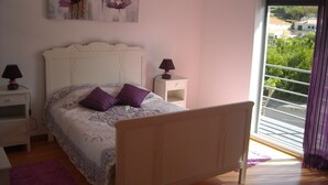A bedroom with a bed, two nightstands, a window with blinds, and a painting on the wall.