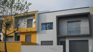 A modern two-story building with a yellow and grey facade, large windows, and a visible garage door.