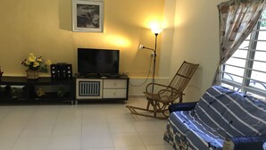A living room with a sofa, a television, a lamp, a chair, and a wall-mounted picture. - Bukit Bentong Homestay (Bentong)