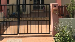 A two-story building with a gated entrance, a balcony on the upper floor, and a small garden area. - Bukit Bentong Homestay (Bentong)
