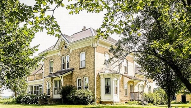 A large, two-story house with a symmetrical facade, multiple windows, and a well-maintained lawn. - 150 Year Old Home Situated in the Picturesque Rolling Hills of Southwest WI (Lone Rock)