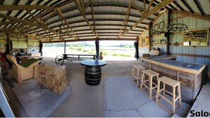 A rustic bar area with wooden stools, a bar counter, and a large barrel. - 150 Year Old Home Situated in the Picturesque Rolling Hills of Southwest WI (Lone Rock)