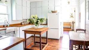 A kitchen with white cabinets, a wooden table, and a refrigerator. - 150 Year Old Home Situated in the Picturesque Rolling Hills of Southwest WI (Lone Rock)