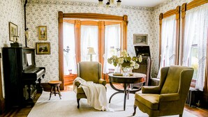 A room with a piano, two armchairs, a table with a vase, and a fireplace. - 150 Year Old Home Situated in the Picturesque Rolling Hills of Southwest WI (Lone Rock)