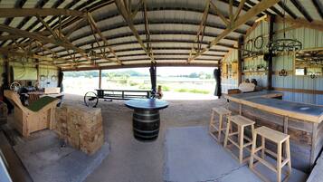 Un coin bar rustique avec des tabourets en bois, un comptoir et un grand tonneau.
