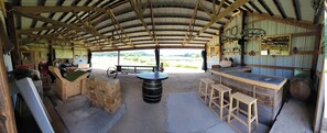 Un coin bar rustique avec des tabourets en bois, un comptoir et un grand tonneau.
