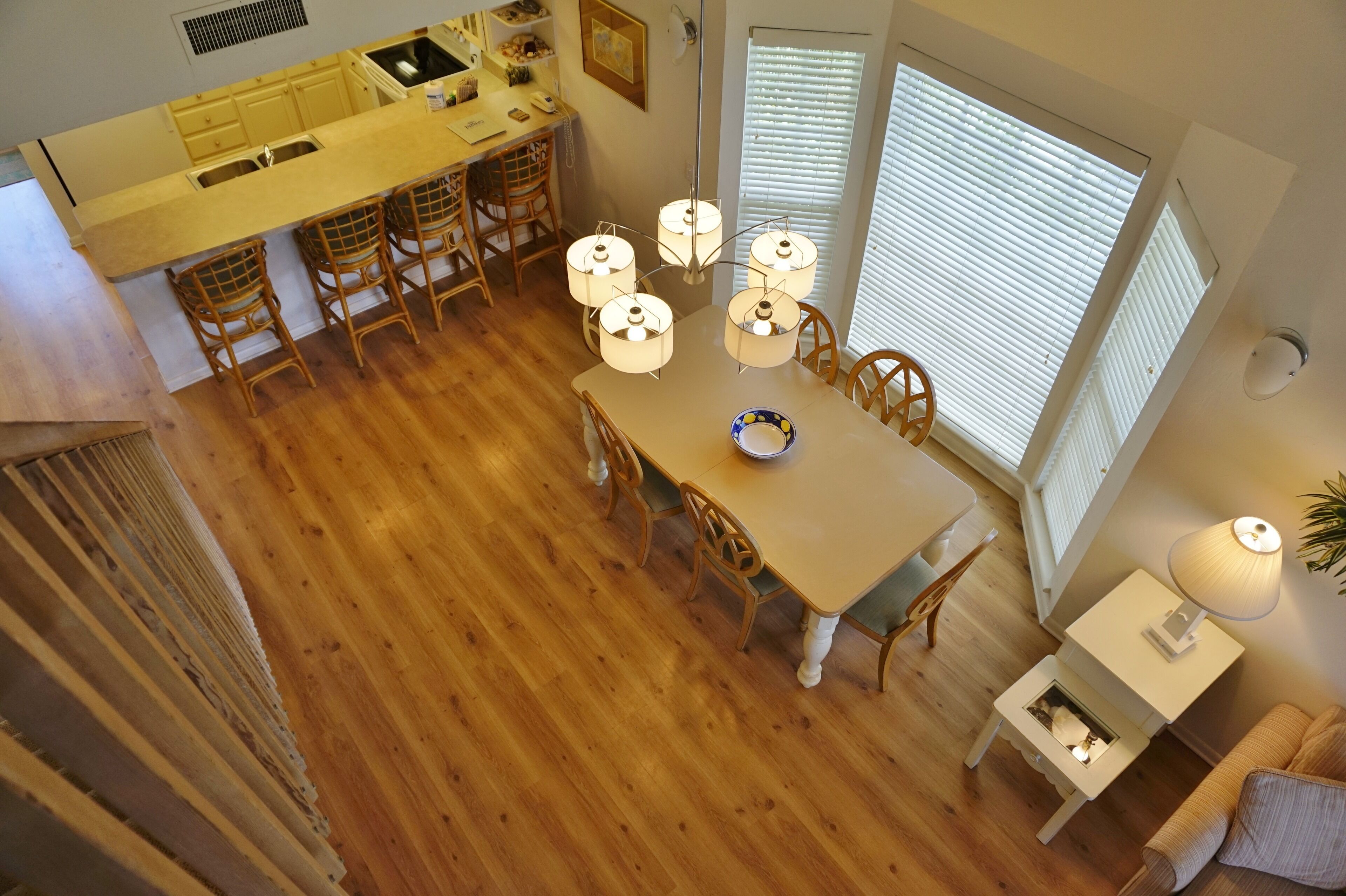 Un comedor con una mesa de madera, cuatro sillas, una araña y vistas a la cocina.