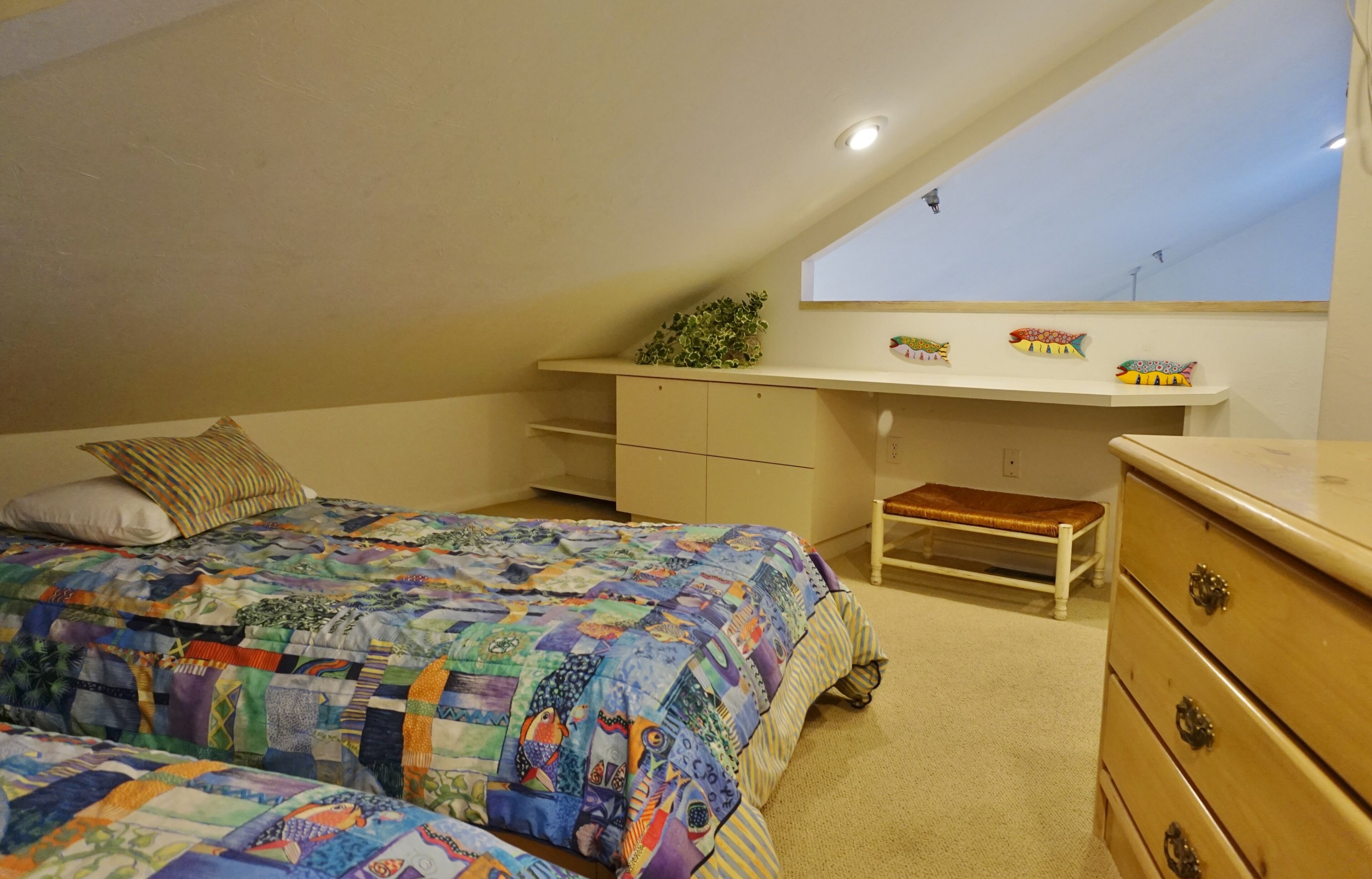 Een slaapkamer met een bed, een bureau, een bankje en een dressoir.