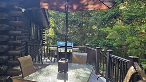 Eine Terrassenausstattung mit Tisch, Stühlen, Grill und Sonnenschirm.