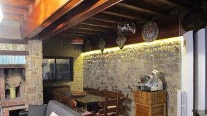 A cozy living area with a stone wall, a fireplace, a sofa, a dining table, and a coffee machine. - Luxury Villas in Sicily with pool (Cefalù)