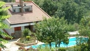 A house with a tiled roof, surrounded by lush greenery and a swimming pool. - Luxury Villas in Sicily with pool (Cefalù)