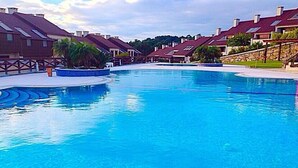 A large swimming pool with a clear blue water surface, surrounded by modern buildings with red roofs and stone walls. - BEACH FRONT, SPA, SWIMMING POOLS, TENNIS, PADDLE, LARGE GARDEN, PLAYGROUND, CHILDREN'S PLAYGROUND, PLAYGROUND, TENNIS COURTS, PADDLE, LARGE GARDEN, CHILDREN'S PLAYGROUND, CHILDREN'S PLAYGROUND, CHILDREN'S PLAYGROUND. (O Grove)