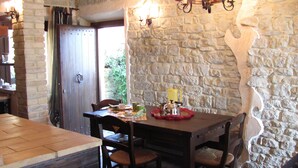 A rustic dining area with a stone wall, wooden table, and chairs. - Stone Casale Apartment with Pool & Terrace: Sibillini to Sea View (Penna San Giovanni)