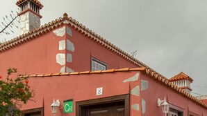 A building with a red facade, a brown door, and a staircase leading to the entrance. - Detached cottage with two terraces and views of sea and mountains (Puntallana)