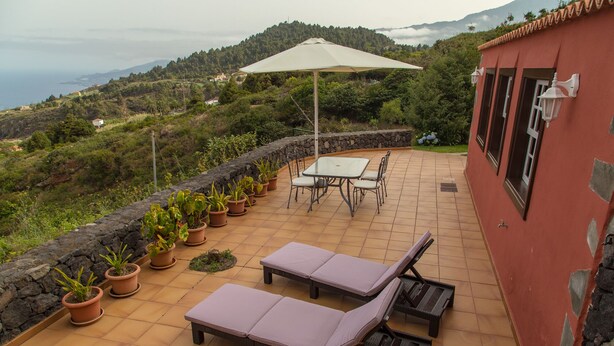 A patio with a table and chairs, two lounge chairs, and potted plants. - Detached cottage with two terraces and views of sea and mountains (Puntallana)