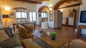 Un salón espacioso con un sofá, sillones, una mesa de centro y una cocina al fondo.