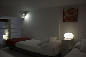 A bedroom with a bed, bedside tables, a wall-mounted light, and a painting.