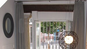 Un salon avec un canapé noir, une table basse en verre et un luminaire suspendu.