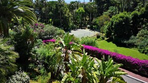 A tennis court surrounded by lush greenery and a view of the sea. - Luxury building with swimming pool and sea access (Vallauris)