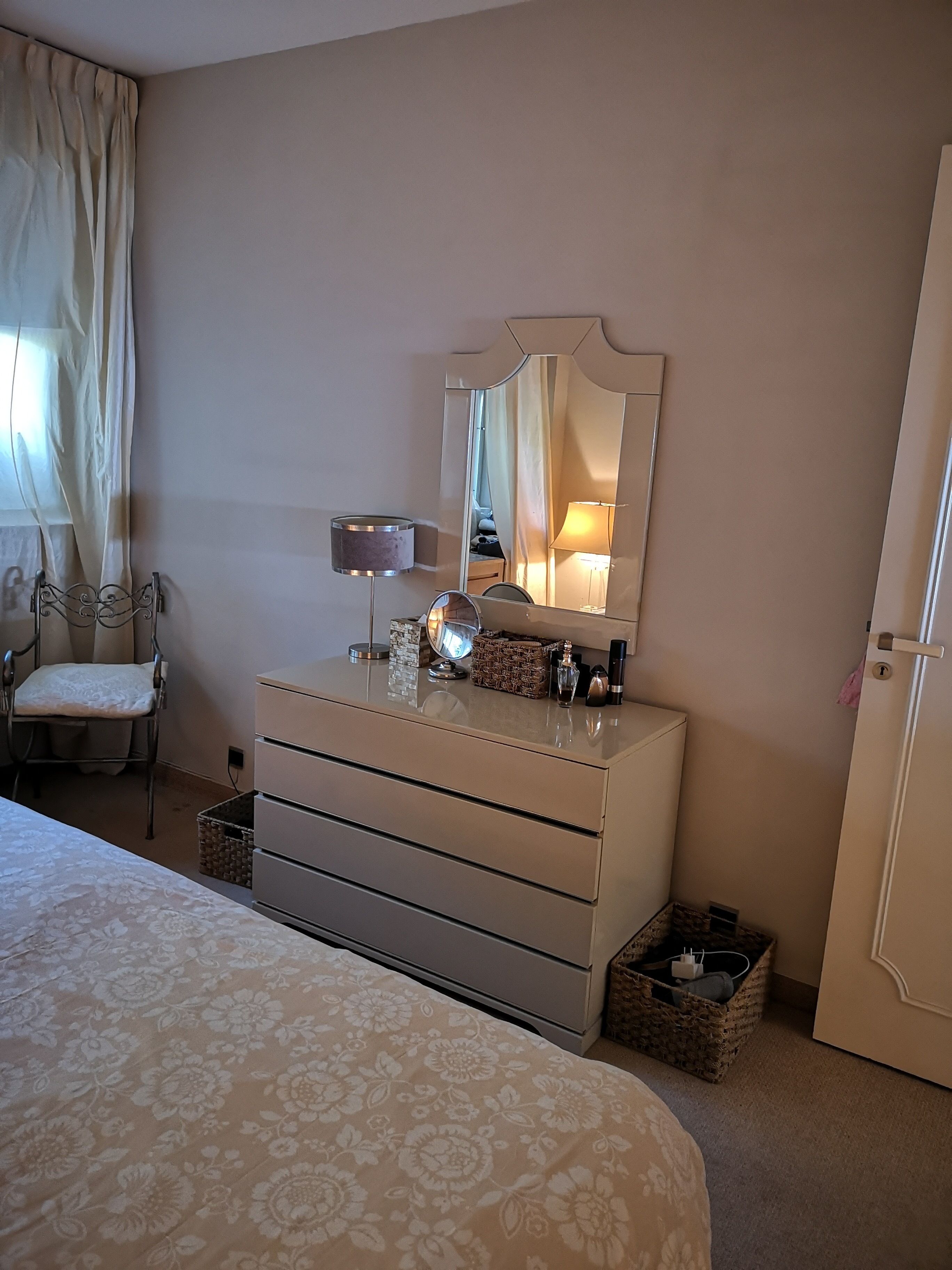Une chambre à coucher avec un lit, une commode, une chaise, un miroir et une lampe.